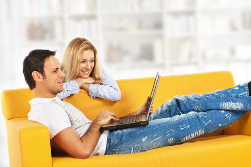 a couple on a couch looking at a laptop
